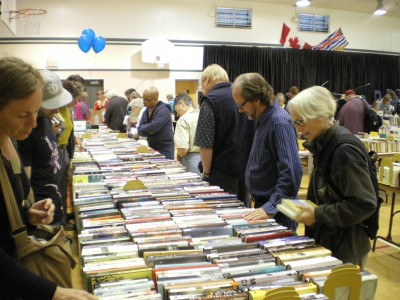 people browsing books on tables in the school gym at the book fest book sale fundraiser.