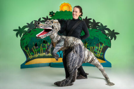 woman in dinosaur costume with a forest prop background.
