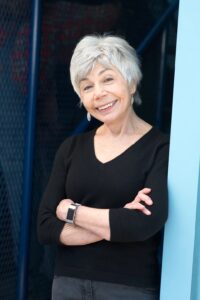 author photo of Jane in black with arms crossed and smiling.